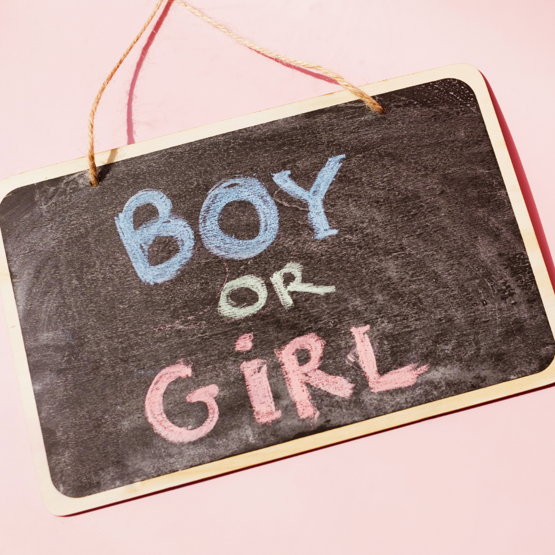Blackboard with "BOY or GIRL" in colorful chalk on pink background, playful theme