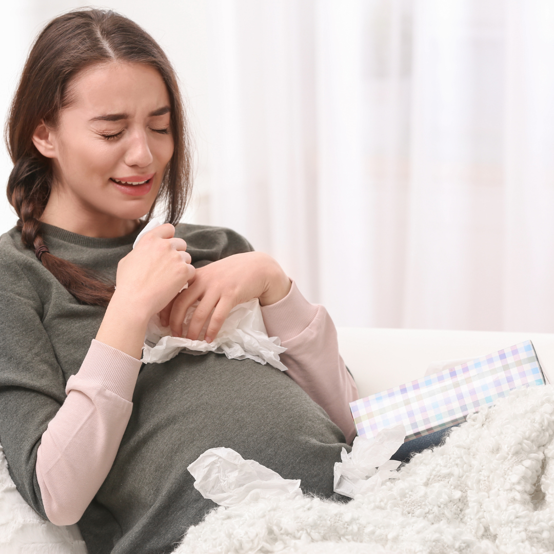 Young woman with tissue on sofa holding smartphone, gift box nearby, looks distressed
