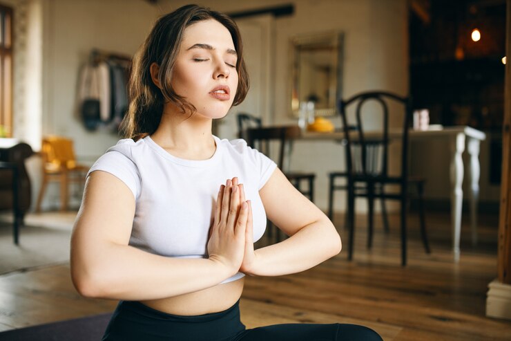 Woman practicing yoga on a black mat in a serene room with yellow chair