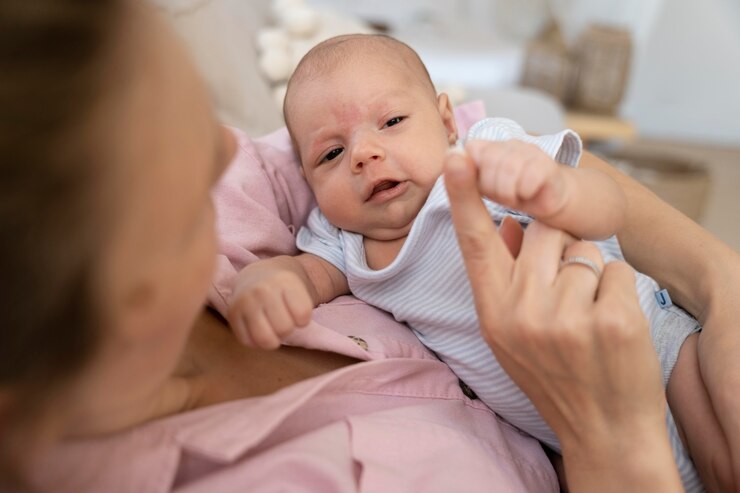 Mother holding newborn in pink shirt, focusing on nurturing bond; breastfeeding guide