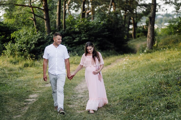 Couple strolling hand in hand through lush green forest, capturing early pregnancy symptoms joy