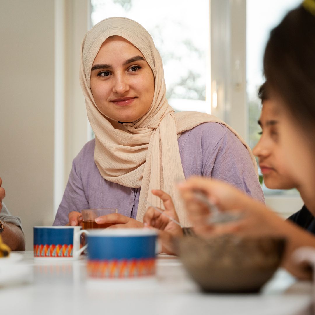 Young woman in hijab enjoying a meal in warm lighting, Ramadan preparation theme.