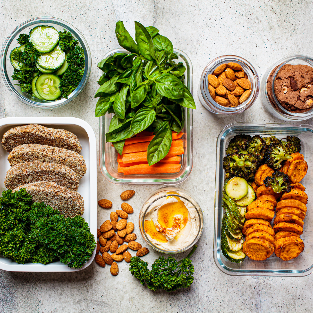 Colorful postpartum clothing meal prep with veggies, nuts, hummus, and cookies.