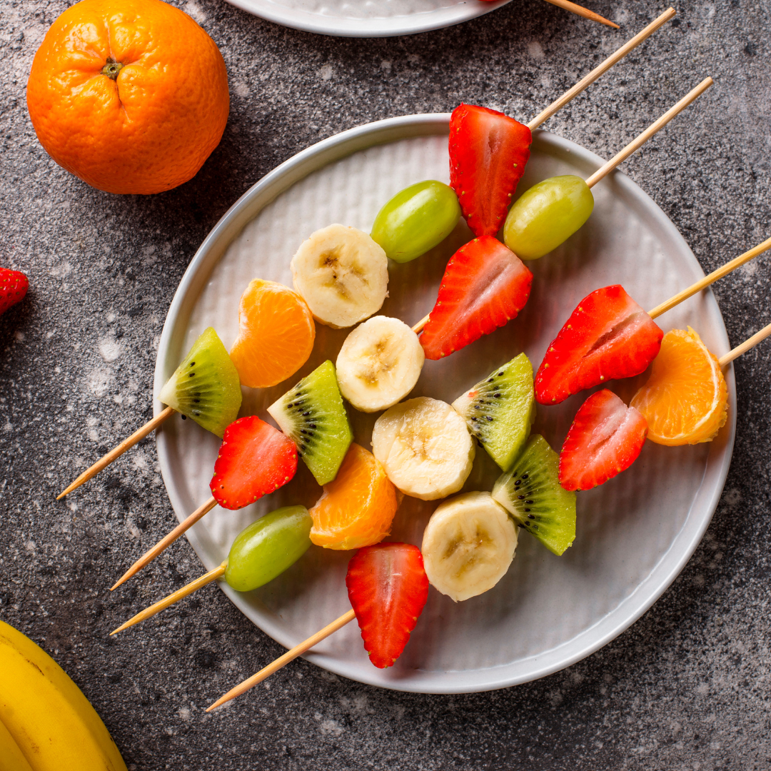 Colorful fruit skewers on white plate, vibrant health snack on dark counter