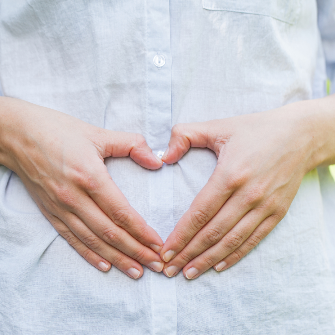 Hands forming heart shape with love theme, calm blue shirt; probiotics for pregnancy.