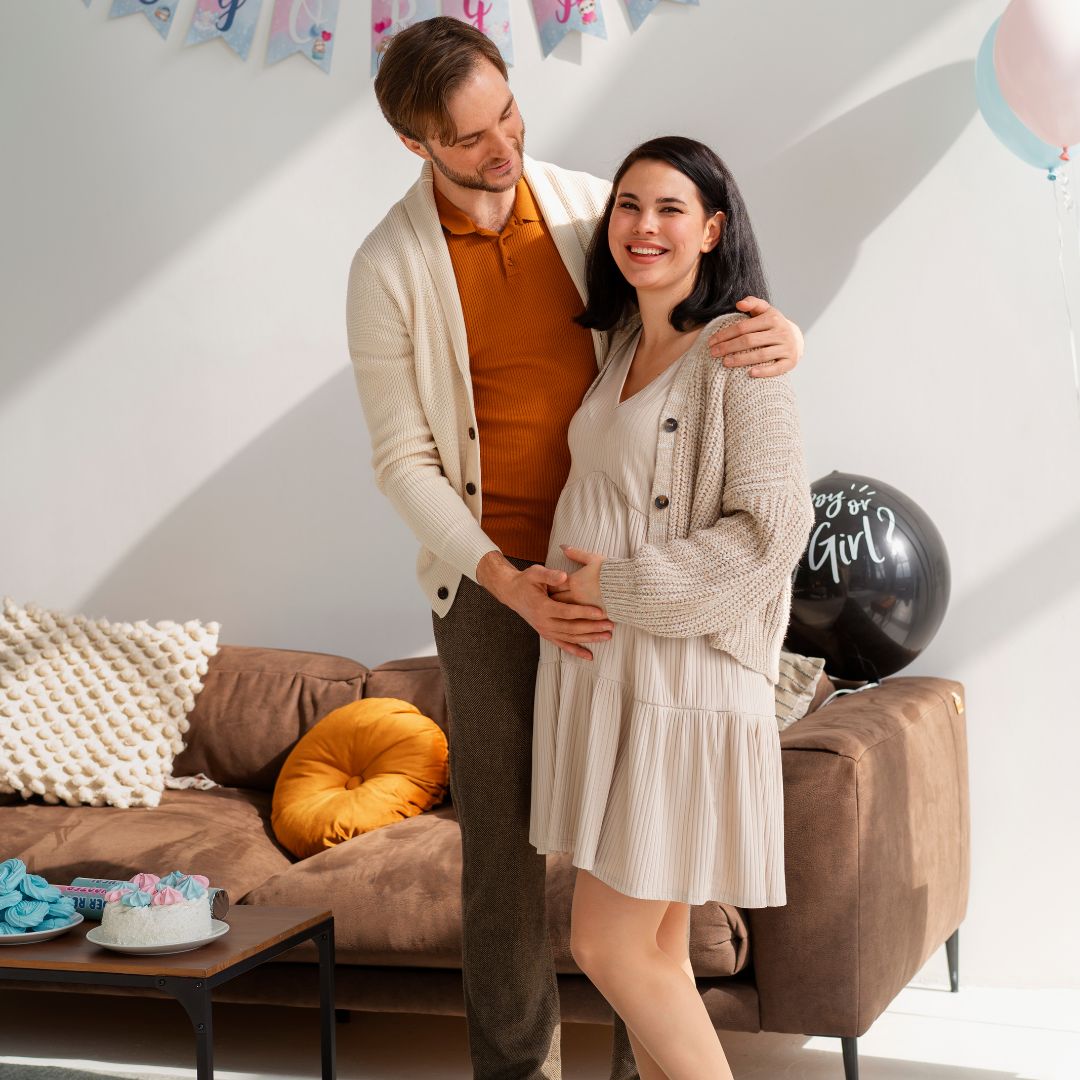 Couple celebrating baby shower in a blue and white themed room with cake and balloons