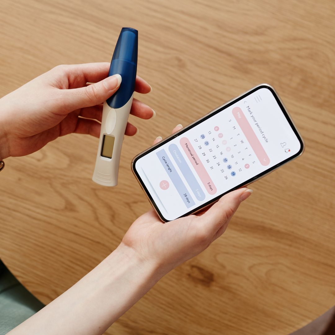 Person using digital pregnancy test and smartphone app for reproductive health tracking