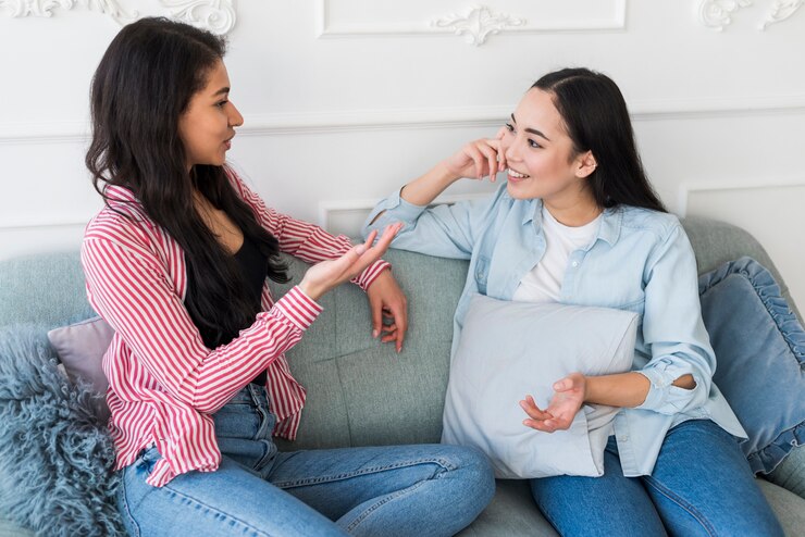 Women discussing Best Practices on a gray couch in a casual setting