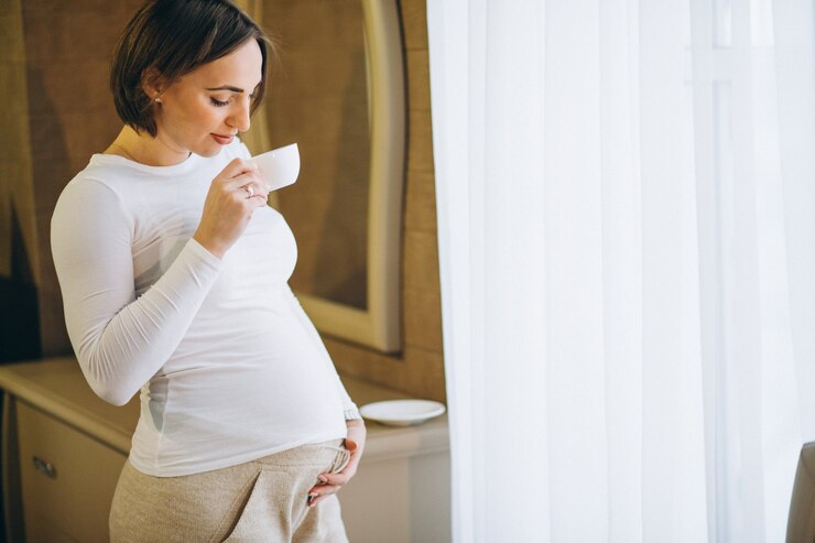 Pregnant woman in white top enjoys tea, highlighting Mom Safety Solutions' serenity